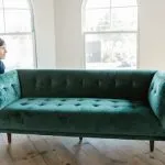 Movers lifting a sofa to help you move after choosing between furnished vs unfurnished apartments in Brooklyn